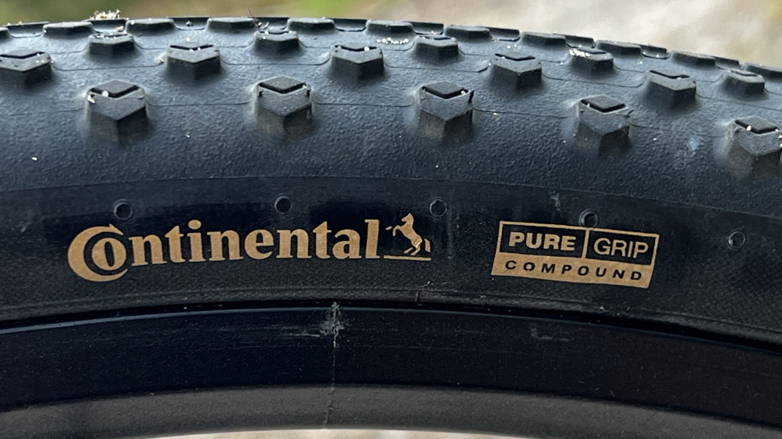 Makrofotografia boku opony Continental. Złote logo marki i napis 
