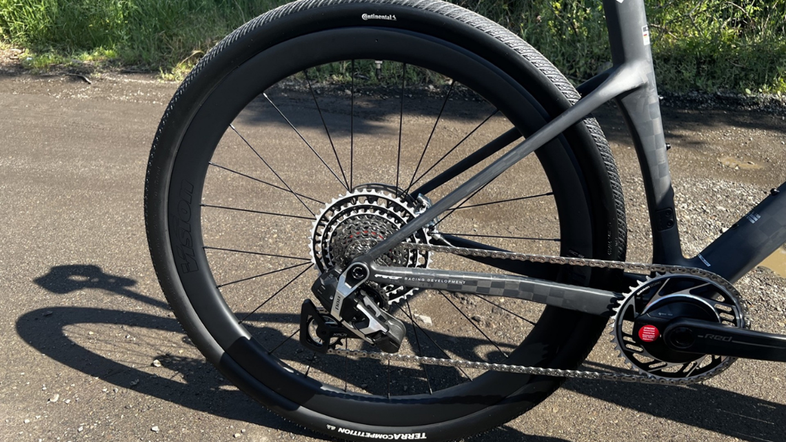 Tylne koło roweru gravelowego z oponą Continental Terra Competition zamontowaną na głębokiej, czarnej karbonowej obręczy marki Vision.