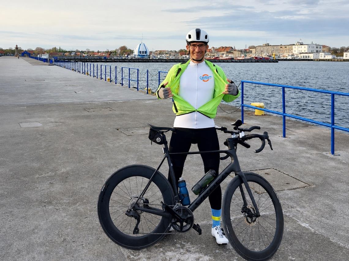 Jacek Kwiatkowski w koszulce centrumrowerowe.mom, obok stoi rower
