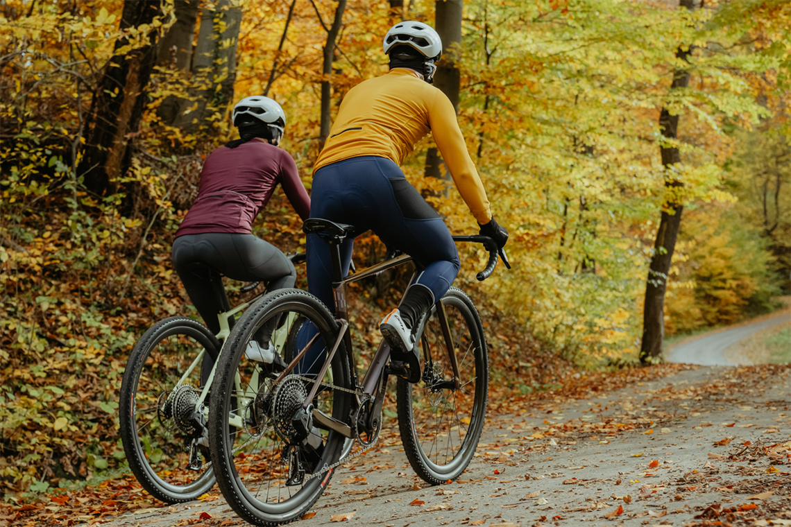 Para rowerzystów jedzie podjazdem wśród spadłych liści jesienią.